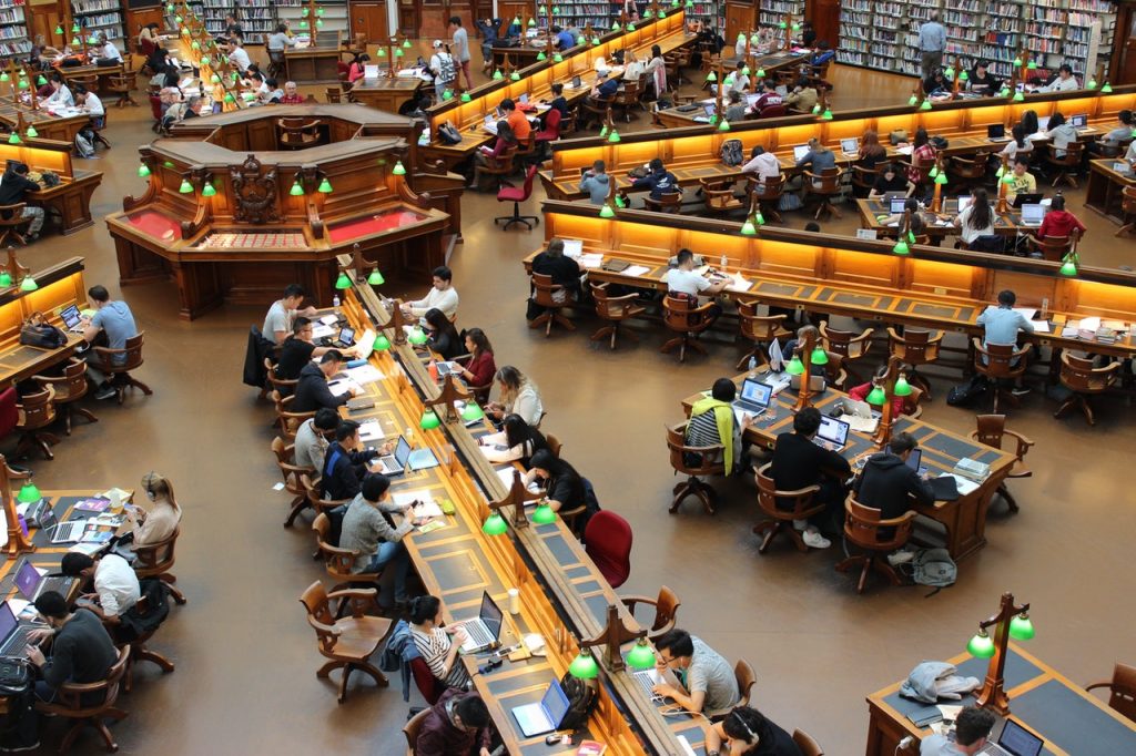Fotografia de uma biblioteca com diversas pessoas estudando.