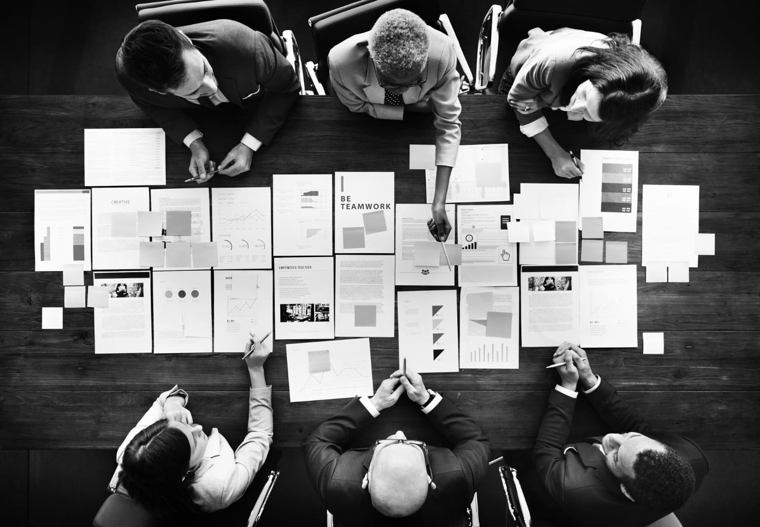 Planejamento estratégico de marketing: o que é e como fazer? Pessoas sentadas em uma mesa de reunião, analisando estatísticas.