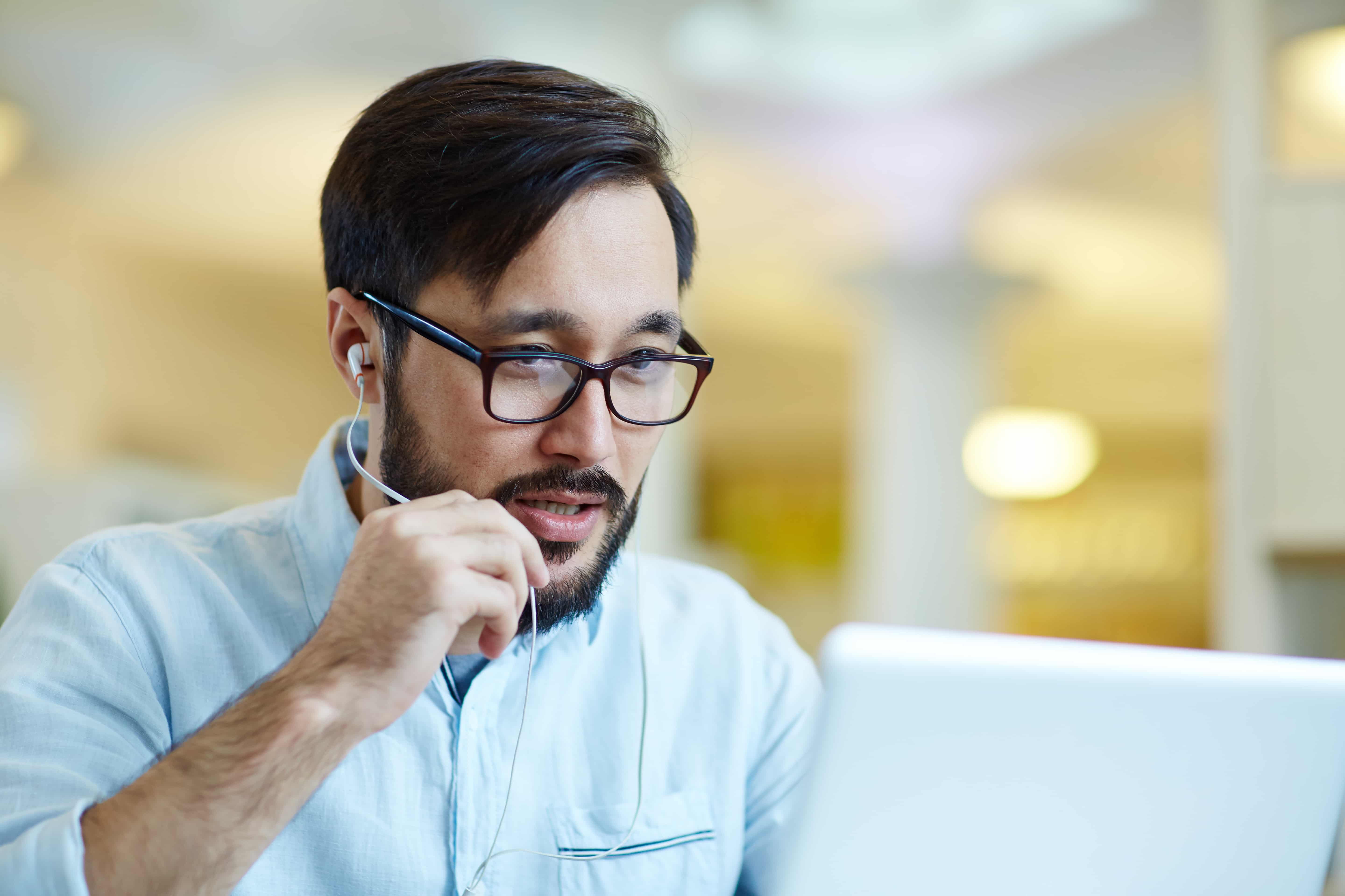 Homem olhando para tela de notebook, participando de conversa por videoconferência.
