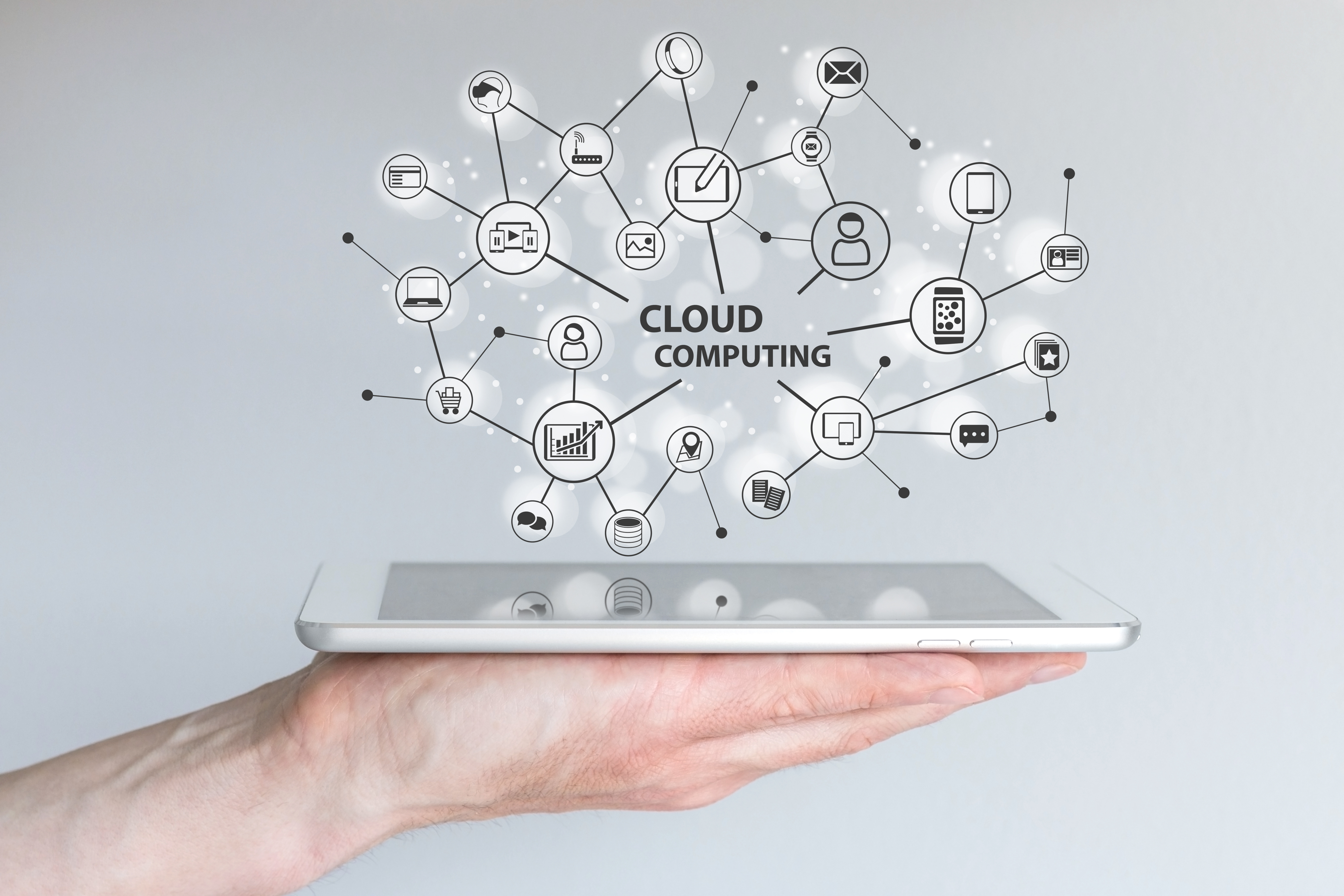 Mão segurando tablet deitado, dele saindo ícones computacionais e as palavras cloud computing.
