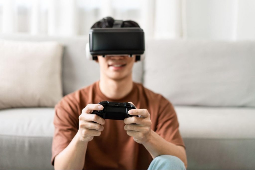 Homem sentado com um óculos de realidade virtual e um console em mãos