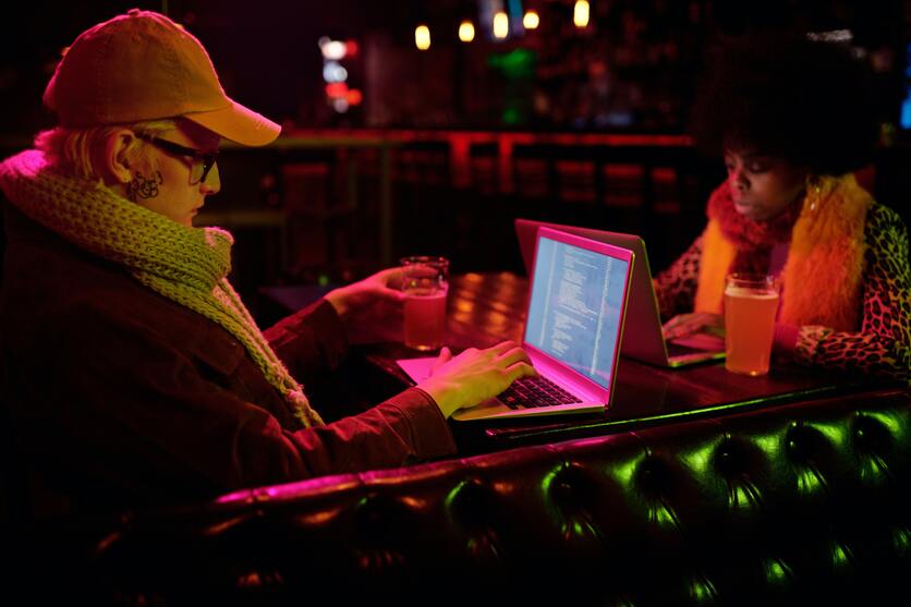Duas pessoas em um bar olhando para um notebook e vendo linguagens de programação