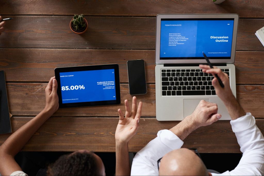 Duas pessoas me uma mesa olhando para dados em um tablet e em um notebook para ilustrar O Cisco Meraki