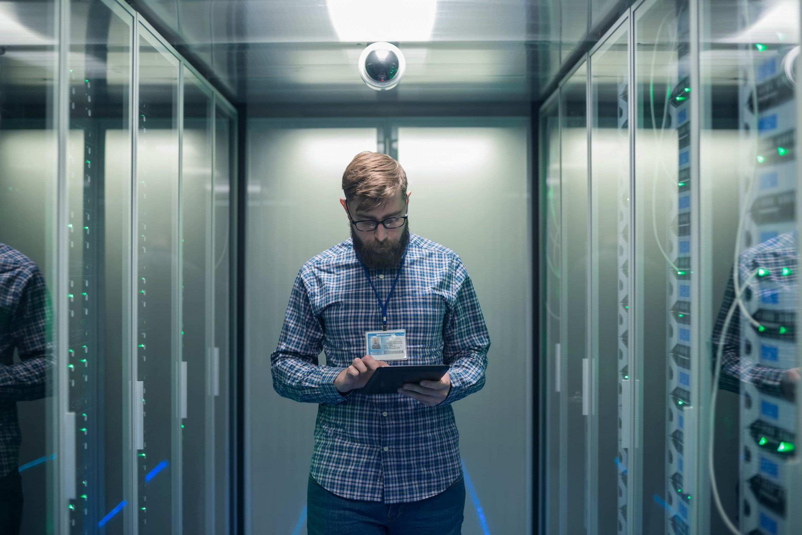 Homem branco de óculos com tablet em mãos dentro de um centro de serviços.