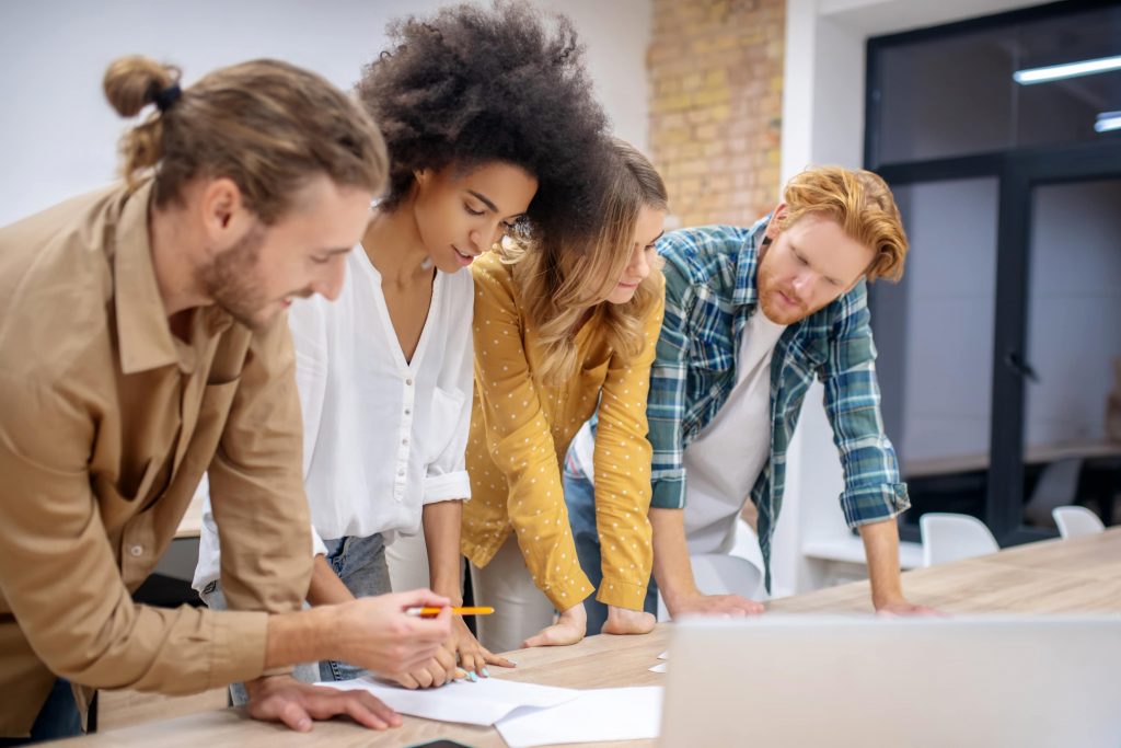 Grupo diverso em escritório encara papéis sobre a mesa.