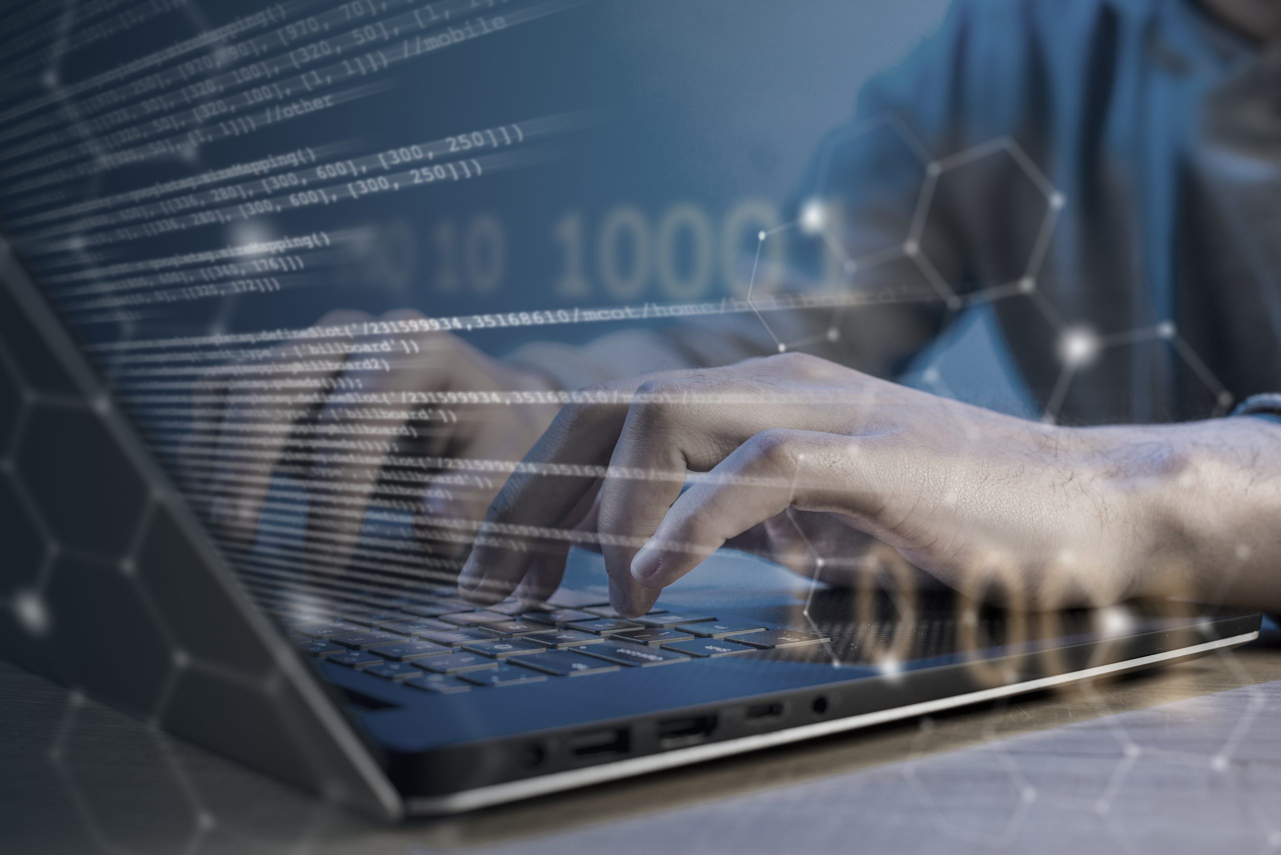 Data mesh: o que é e como funciona? Visão das mãos de um profissional da tecnologia trabalhando em um computador, enquanto dados e informações sobrepõem a imagem.