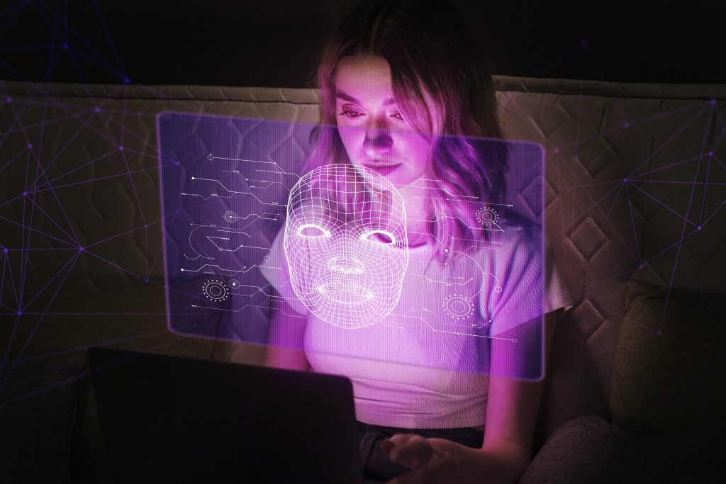 Mulher sentada em sofá, utilizando notebook, enquanto imagem de identificação facial em roxo aparece em sua frente.