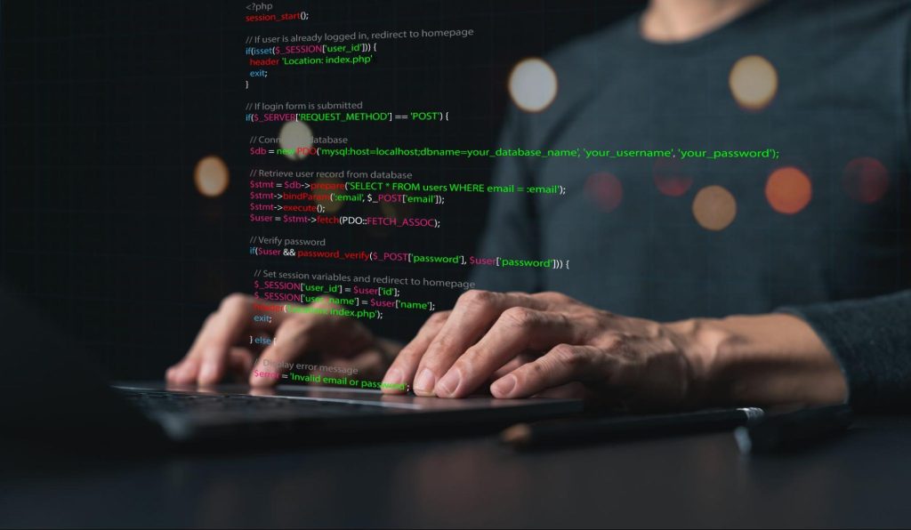 mãos masculinas digitam em teclado disposto sobre superfície escura. Dados relacionados ao algoritmo permanecem à frente da imagem