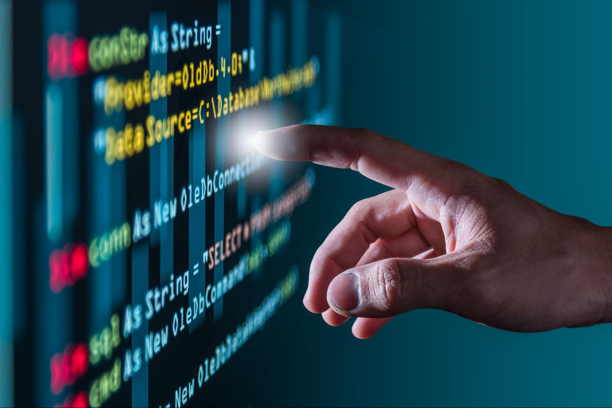 Mão humana toca tela escura com códigos sobre tela preta