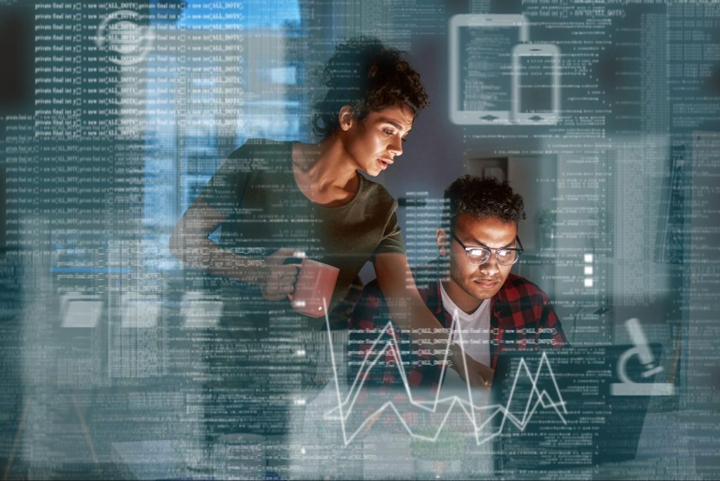 Uma mulher está em pé, segurando uma caneca, enquanto observa um homem sentado à frente de um laptop. O homem usa óculos e parece concentrado em seu trabalho. Ao fundo, há códigos e gráficos sobrepostos, criando uma atmosfera de programação e análise de dados. A iluminação é suave, destacando os rostos dos dois.
